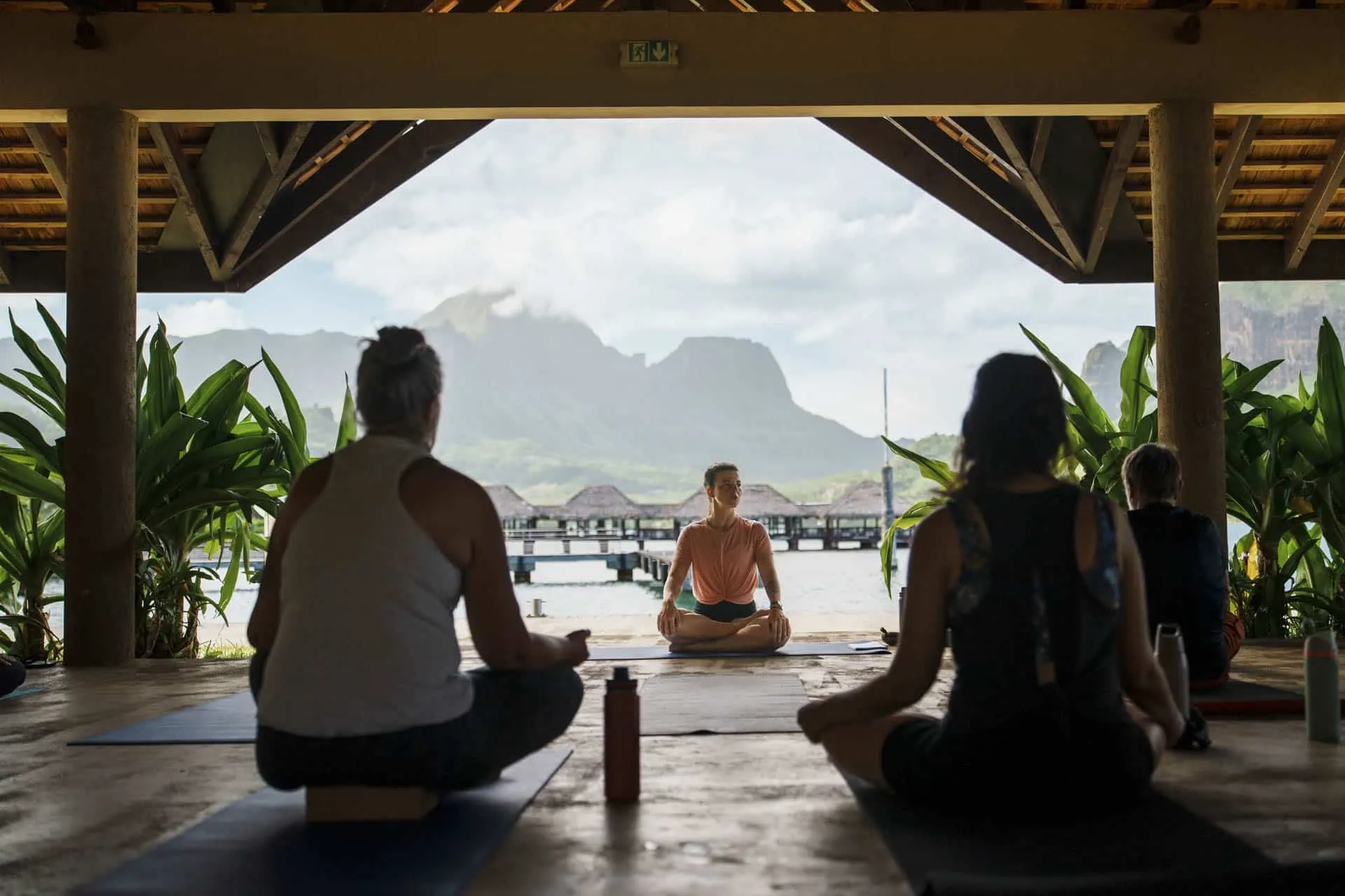 Méditation en groupe sous un fare face aux montagnes